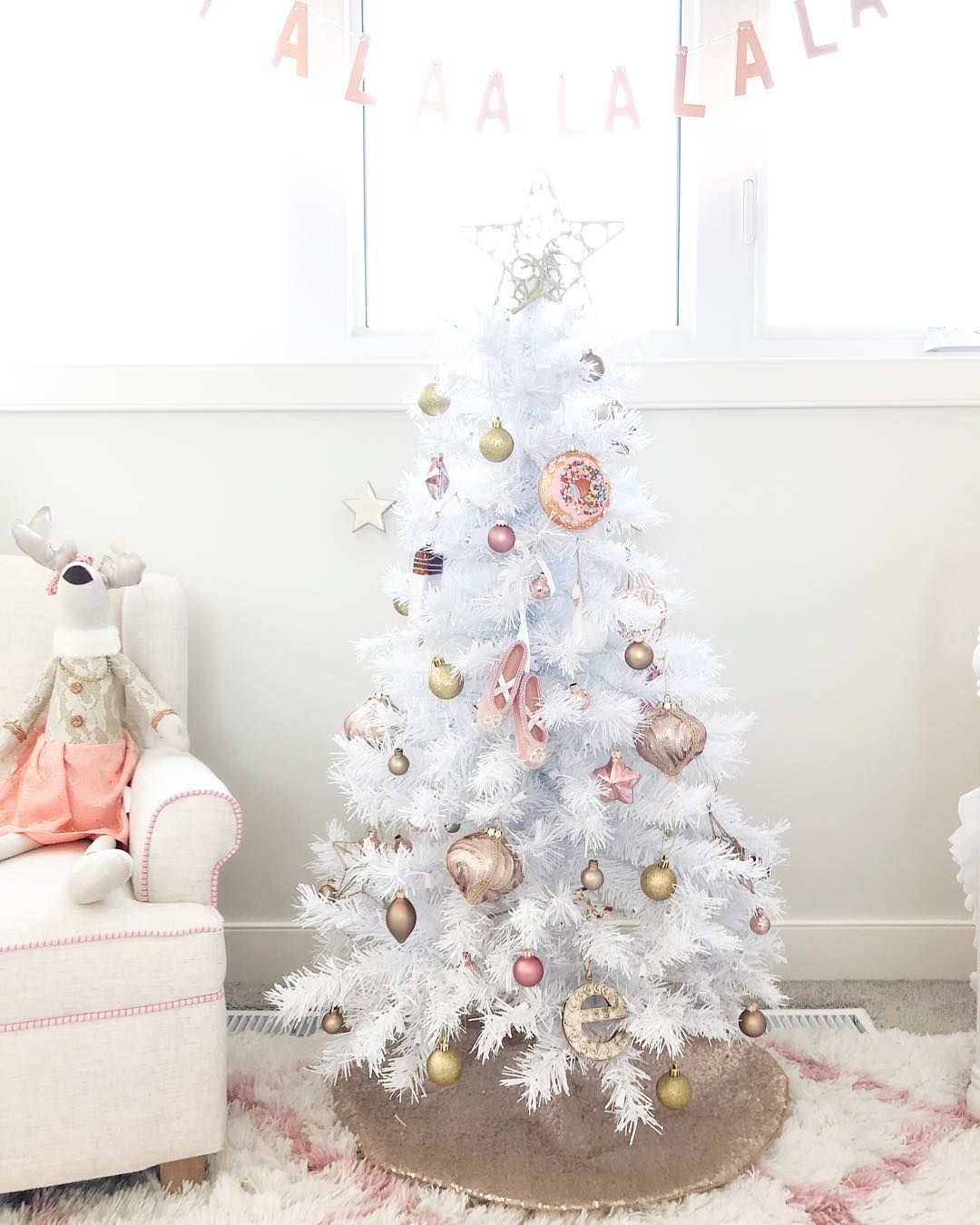 White Christmas tree decorated with metallic-colored ornaments.